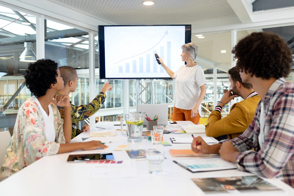 Instructor in classroom setting showing a presentation to adult attendees around table