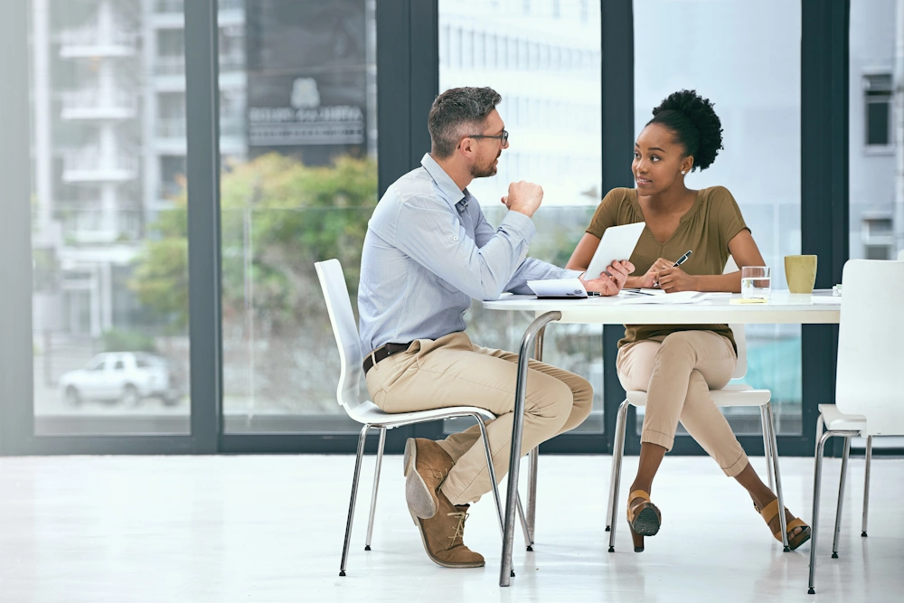 Business man in discussion with business woman at a small office table